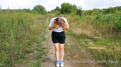 Bottomless girl with pigtails walks along a country road