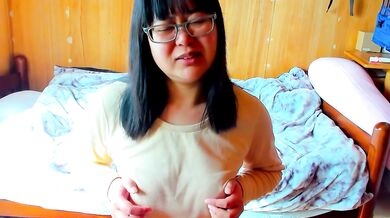 A girl wearing glasses orgasms while masturbating with her nipples, making funny noises.