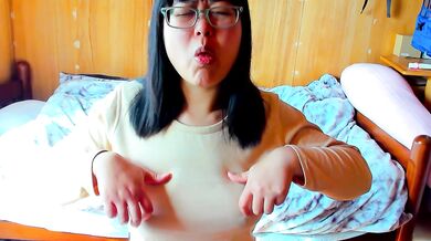 A girl wearing glasses orgasms while masturbating with her nipples, making funny noises.