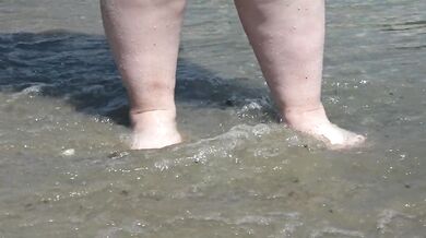 Fat bare legs with red pedicure walk along the bank of the river, fetish.