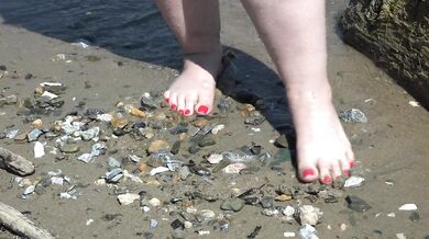 Fat bare legs with red pedicure walk along the bank of the river, fetish.