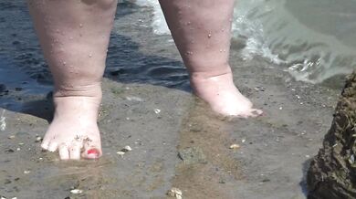 Fat bare legs with red pedicure walk along the bank of the river, fetish.
