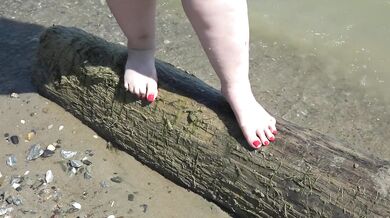 Fat bare legs with red pedicure walk along the bank of the river, fetish.