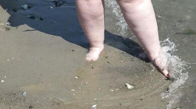 Fat bare legs with red pedicure walk along the bank of the river, fetish.
