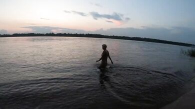 Fishermen swim past a beautiful nudist woman