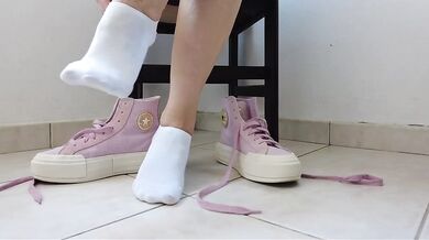 Showing off pink Converse sneakers and white ankle socks