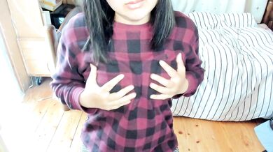 A Japanese woman bites the hem of her clothes to show her breasts and caress her nipples.