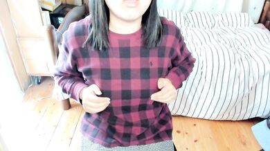 A Japanese woman bites the hem of her clothes to show her breasts and caress her nipples.