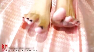 A young lady paints her toenails with black varnish. She is wearing black and white panties and a bl